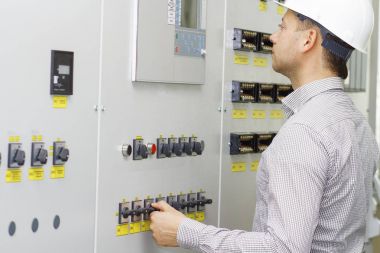 Teknik ekipman denetim mühendisi. Kontrol paneli üzerindeki beyaz kask işçi. Teknoloji sürecini izleme.