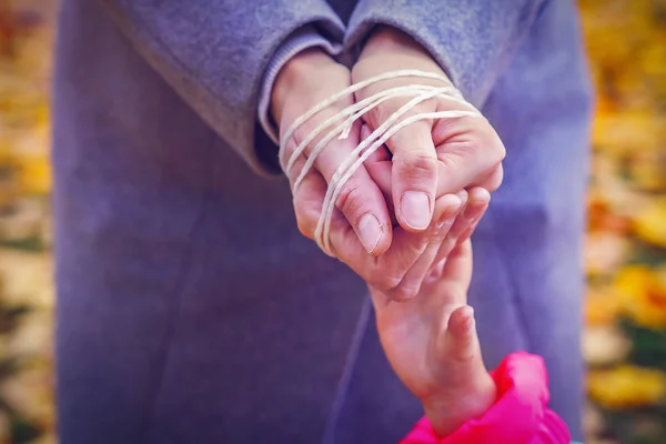 Рука ребенка протягивает руку к связанным веревкой рукам своей матери. Задержание родителя. Насилие в отношении детей . — стоковое фото