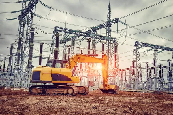 Sarı Ekskavatör santral inşaat sahasında. Endüstriyel elektrik ekipman Ekskavatör Kepçe kazılan yere arka plan.