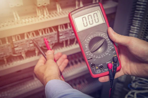 Onderhoudsmonteur met multimeter tester in handen close-up. Elektrische metingen in elektrische kast. Support specialist met test-apparaat — Stockfoto