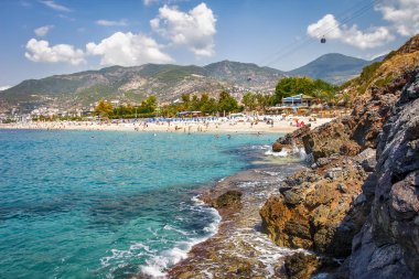 Kayalık deniz güneşli yaz gününde Türkiye'de Alanya Beach. Dağlar ve costline mavi deniz manzara. Sahne cennet defne lagün tropikal plaj