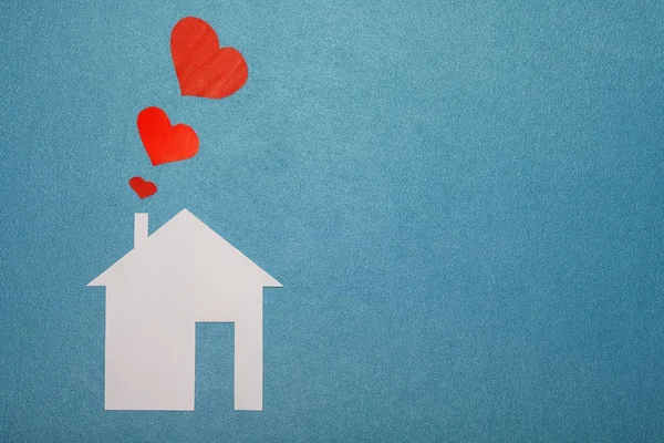 Concetto di amore in casa. Casa di carta bianca su sfondo blu strutturato con cuori rossi da tubo. Fumo da tubo in forma di carta cuori rossi. AMORE, famiglia, casa . — Foto Stock