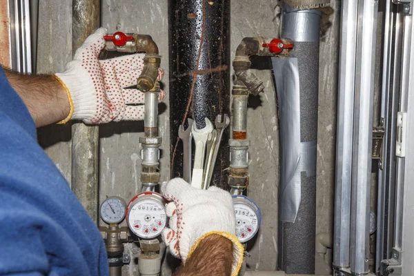 Klempner repariert Rohre im Sanitärbereich. Hände Sanitär mit Schlüsseln auf dem Hintergrund von Rohren, Manometern und Filtern. — Stockfoto