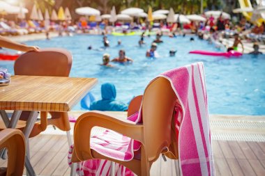 Tropikal resort otel yüzme havuzunda. masa sandalye üzerinde parlak güneşli tatil turist havuzda yüzme ile arka plan bulanık ile