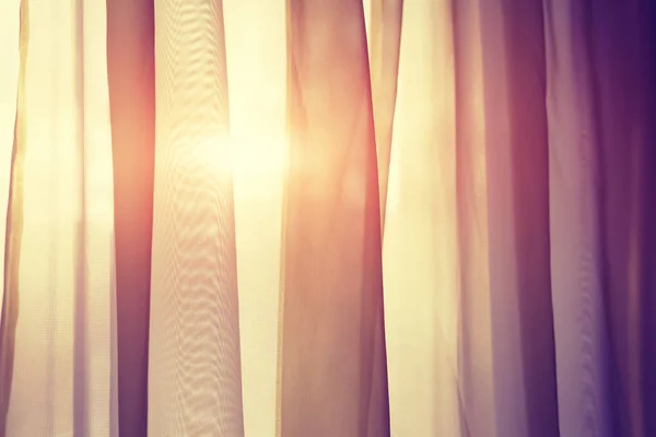 Gordijnen op venster met zon. De zon schijnt door gordijnen bij zonsondergang close-up. — Stockfoto