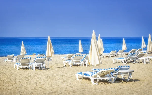 Курортный морской пляж с песчанками и пумбреллами на белом песке в солнечный день. Летние каникулы — стоковое фото