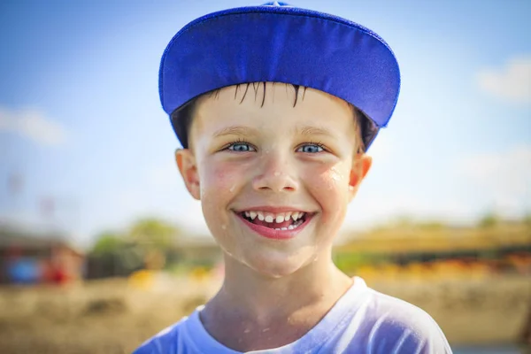 Retrato de niño caucásico feliz en gorra con gotas mojadas en la cara. La cara del niño sonriente después de bañarse en el soleado día de verano — Foto de Stock