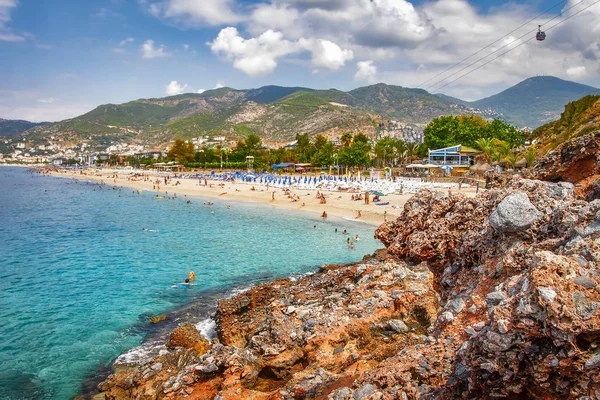 Cennet tropikal resort beach Alanya, Türkiye'de. Deniz ve rocky Dağları bulutlar ile güneşli gün yaz Türk plajda. Yaz tatil dinlenmek.