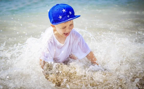 Feliz chico caucásico se está bañando en el mar en las vacaciones de verano. Niño sonriente en agua de mar — Foto de Stock