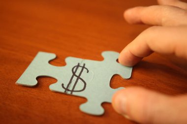 Erkek görüntü dolar işareti ile bulmacalar koyar. El ve Doları yakın çekim ile bulmaca parçaları. Para kavramı olun. İş ve sermaye.