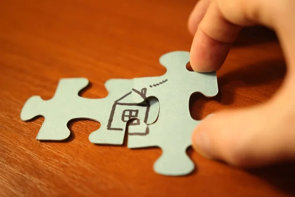 Mano aggiunge pezzi di puzzle per casa primo piano. Costruire concetto di casa. Home comfort e amore . — Foto Stock