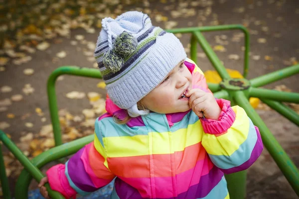Potret bayi perempuan Kaukasia dengan topi dan jaket di korsel pada musim gugur. Seorang anak melihat ke langit . — Stok Foto