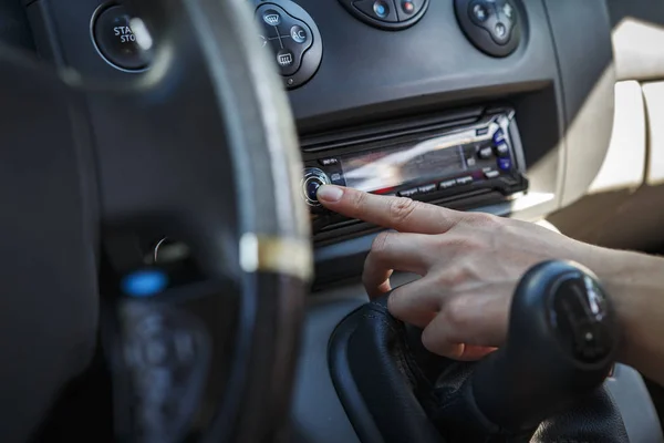車の中の人は、ラジオのボタンを押します。車のダッシュ ボードの背景に手します。. — ストック写真