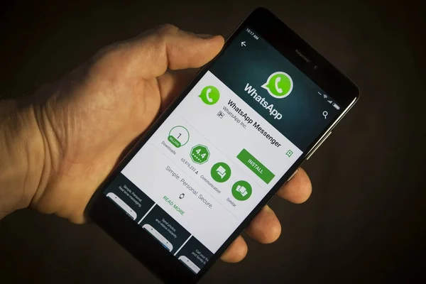 Berlín, Alemania - 19 de noviembre de 2017: teléfono inteligente moderno en la mano con WhatsApp instalar menú en la pantalla con el icono de la aplicación de primer plano. WhatsApp aplicación en el teléfono . — Foto de Stock