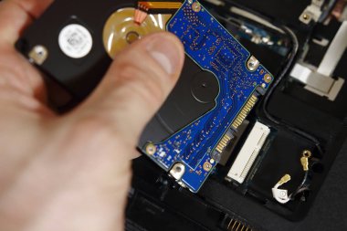 mühendis değişiklikleri zor eski dizüstü bilgisayar yakın çekim içinde sürücü. Mühendisin elle sökülüp dizüstü bilgisayar arka plan üzerinde hdd. Onarım elektronik.