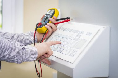 Otomasyon mühendisi multimetre üzerinde Denetim Masası yakın çekim ile elleri. Endüstri/sanayii donatımı otomatik iş istasyonundan servis mühendisi denetler.