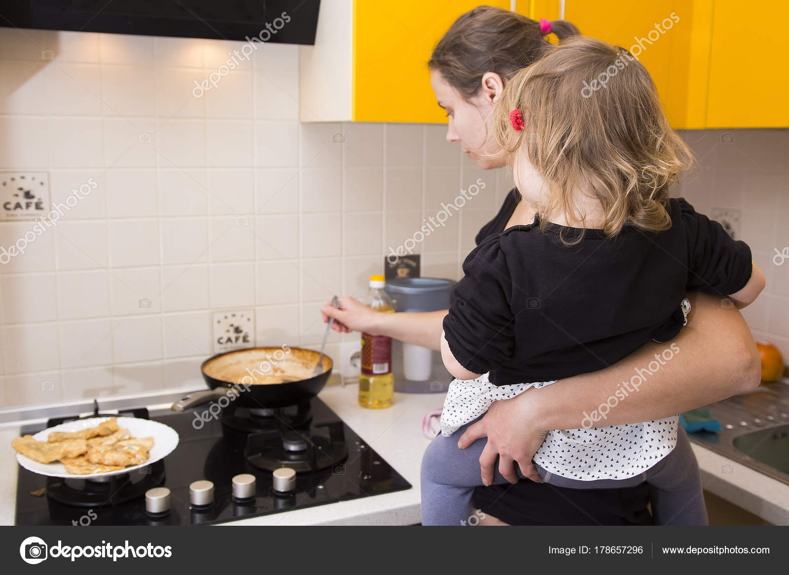 Mom With Baby In His Arms Preparing Food In The Kitchen Housewife With Children Stock Photo Image By Dzmitrock87 Gmail Com 178657296