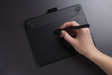 Sanatçı grafik tablet üzerinde çizer. Tasarımcı grafik tablet portre üzerinde çalışır. Eli kalem boya tutar.