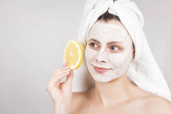 Beauty Skin Care Concept. Wanita Kaukasia yang menarik dengan topeng wajah memegang buah sitrus di tangannya dengan latar belakang putih. prosedur spa dan krim masker pada kulit wajah . — Stok Foto