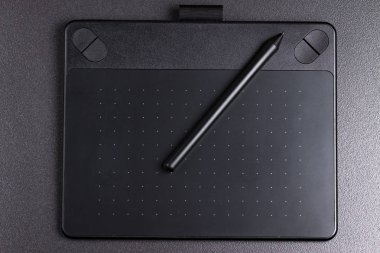 graphic tablet with pen on black background top view. clipart