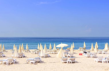Şezlong ve şemsiye resort Beach karşı mavi deniz ve açık gökyüzü parlak güneşli gün. Beach Tatil kavramı. Yaz tatili. Tropikal plaj ve rahatla.