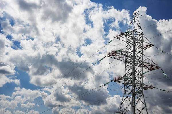 Linea elettrica ad alta tensione sullo sfondo di nuvole e cielo blu. Concetto di ingegneria elettrica ed energetica. Trasmissione di energia elettrica tramite filo . — Foto Stock