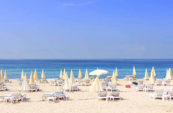 太陽のベッドや青い海に対してリゾート ビーチ パラソル、明るい晴れた日に晴天。ビーチ休暇の概念。夏休み。熱帯ビーチし、リラックス. — ストック写真