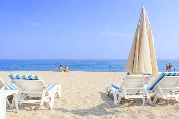 Ligbedden en parasol op zee strand met wit zand op de achtergrond van de zee en blauwe heldere hemel. Zomervakantie op tropisch strand concept. — Stockfoto