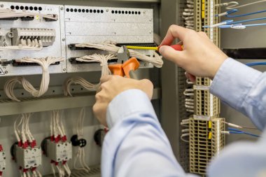 Elektrikçi elektrik kutusu terminal, teller ve denetleyicileri koruma ve otomasyon endüstriyel ekipmanlar ile karşı elinde tornavida ve Tel kesiciler.