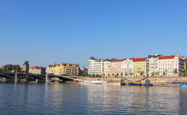 Kilátás Prágára a Moldva-folyó a világos, napsütéses nyári napon. Városi táj Prága épületek és a híd, a prágai folyón. — Stock Fotó
