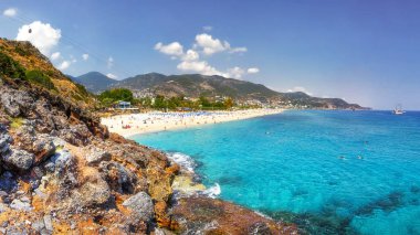 Açık güneşli Akdeniz deniz manzara. Sandy beach, kaya, mavi gökyüzü, dağlar ve deniz. Paradise Bay Alanya'da. Tropikal resort yaz tatili için. Sahil deniz resort Beach.