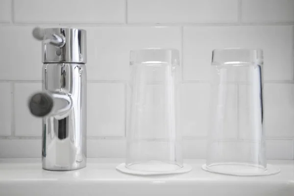 Βρύσης μίξερ και δύο καθαρά ποτήρια νερού στο λευκό μπάνιο — Φωτογραφία Αρχείου