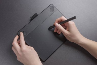 Kız grafik tablet yakın çekim çizer. Grafik tablet, eller ve kalem Üstten Görünüm.