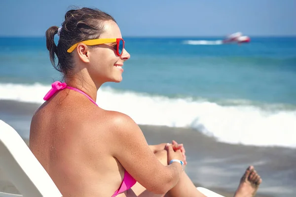 Приваблива молода жінка в сонцезахисних окулярах на березі моря. Дівчина на пляжі купається на блакитному морі в ясний сонячний день. Концепція пляжного відпочинку. Літні канікули в тропічному курорті . — стокове фото