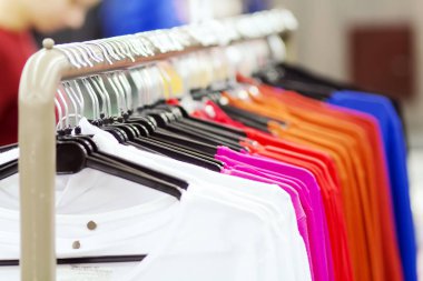 Elbise askıları moda deposunda bir satırındaki asmak. Trendy butik şık şeyler. Yeni giysiler alıyor. Alışveriş kavramı.