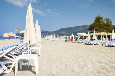 Tropikal resort kumlu plaj arka plan. Seçici odak. Deniz sahil yakınında dağlar yaz tatili. Parlak açık gün beyaz kum plaj.