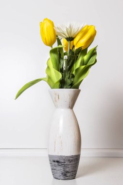 Bir Vazoda Çiçekler yaşıyorum. Sarı laleler ve beyaz duvar arka plan karşı bir tablo üzerinde bir vazoda krizantem.