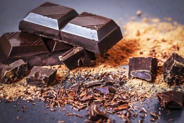 Çikolata. Bir arka plan siyah yakın çekim üzerinde koyu çikolata ve cacoa toz parçalarını. Çikolata parçaları makro.