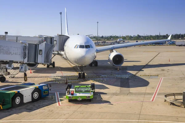 Preparing aircraft for flight. Servicing of aircraft at the airport. The plane in the terminal of the airport on a clear salty day. Loading luggage and boarding passengers in the airplane. Royalty Free Stock Images