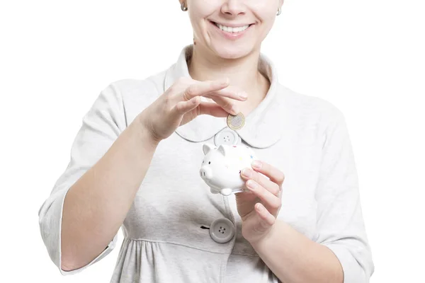 girl lays coin in piggy bank. Collect and keep money at home. Piggy bank and coins concept. Woman with piggy bank and coin close-up isolated on white background
