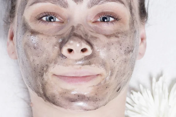 Woman in spa closeup. Face of young girl with black facial mask on spa treatments. Skin care. Skincare. Beauty and health concept. Purification of pores on face. Clean skin. — Stock Photo, Image
