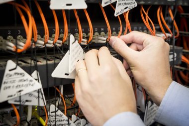 mühendisin el ile optik yama kablosu Close-Up geçiş yapmak için bağlı. Veri Merkezi donanımı kurma. Optik kablolar bağlanma. El ile ağ telekomünikasyon hizmet işçisi 