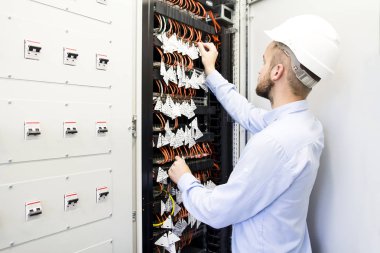 Veri merkezinde hizmet mühendisi. Optik kablolar anahtarları yakınındaki bir kask işçi. Veri merkezindeki telekomünikasyon mühendis. Bilgisayar ağ donanımları ve veri ambarları ayarlama.