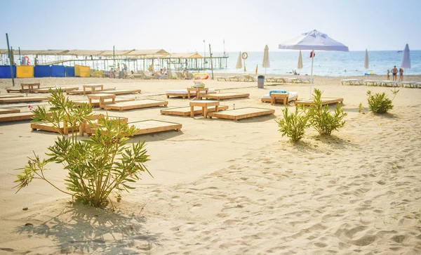 Zandstrand op blauwe zee achtergrond. Parasols en ligstoelen op de oever van de zee. Zomerdag op strand rest. Vakantie concept. Kijk op zee strand in zonnige heldere dag in Turkije-Konakli. — Stockfoto