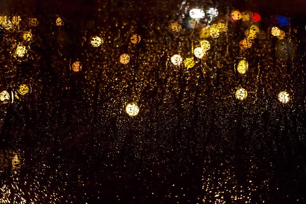 Φωτεινό λαμπερό bokeh στο υγρό γυαλί υπόβαθρο της πόλης το βράδυ φωτίζεται από φώτα και φανάρια. Σταγόνες στο υγρό γυαλί. Σκοτεινή νύχτα φόντο με έμφαση σε γυαλί μετά από βροχή. Μαγική λάμψη bokeh. — Φωτογραφία Αρχείου