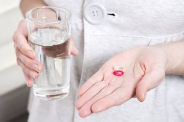 bardak saf su ve iki vitamin tabletleri kızın elinde. Hapları el ve bardak su yakın çekim. Sağlık bakımı. Hapları.