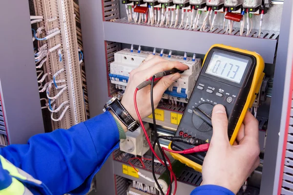 Multimeter is in handen van de engineer in elektrische kast. Aanpassing van geautomatiseerde controlesysteem voor industriële gereedschappen stuurkasten. elektricien maatregelen spanning door tester. — Stockfoto