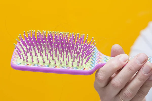 Hair on comb in girl\'s hand. Broken hair. Weak and fragile hair concept. Hair fall out. Woman holding comb with hair in hand.