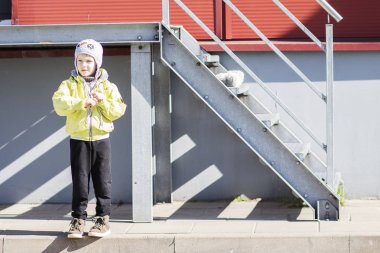 şapkasını ve ceket yakınındaki metal merdiven görünüyor mesafe içine çocuk. Çocuk evin büyük şehirde avluda.