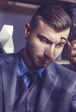 Cesur adam portresi yakın çekim düşünceli trendy şık saç modeli ile uygun ve pipo içiyor. yakışıklı şık genç adam sigara içiyor. Sigara dumanı ve erkek manken.